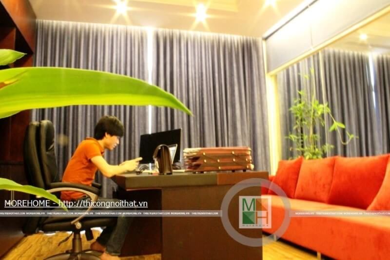 Phòng giám đốc với nội thất sofa bành màu đỏ, bàn làm việc, kệ tài liệu chạm trần,...